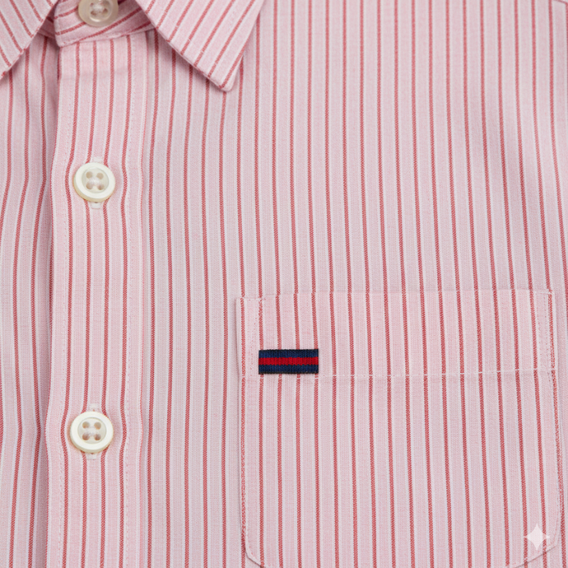 Close-up of a pink striped men’s shirt showing button stitching, fine lines, and fabric texture.
