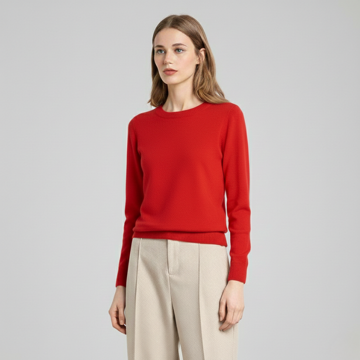 Female model in a red crewneck sweater paired with neutral trousers, captured in a clean studio setting.