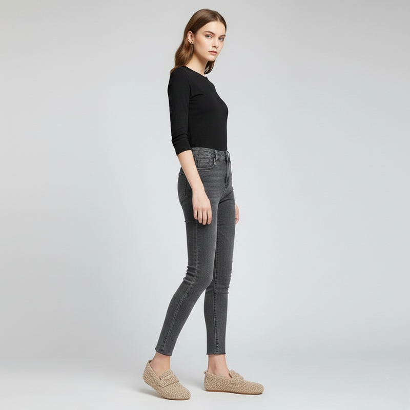 Woman wearing gray jeans and a black top on a light gray background