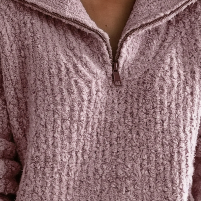 Nahaufnahme des rosa Strickpullovers mit grob gestrickter Oberfläche und sichtbarer Kragenverarbeitung.
