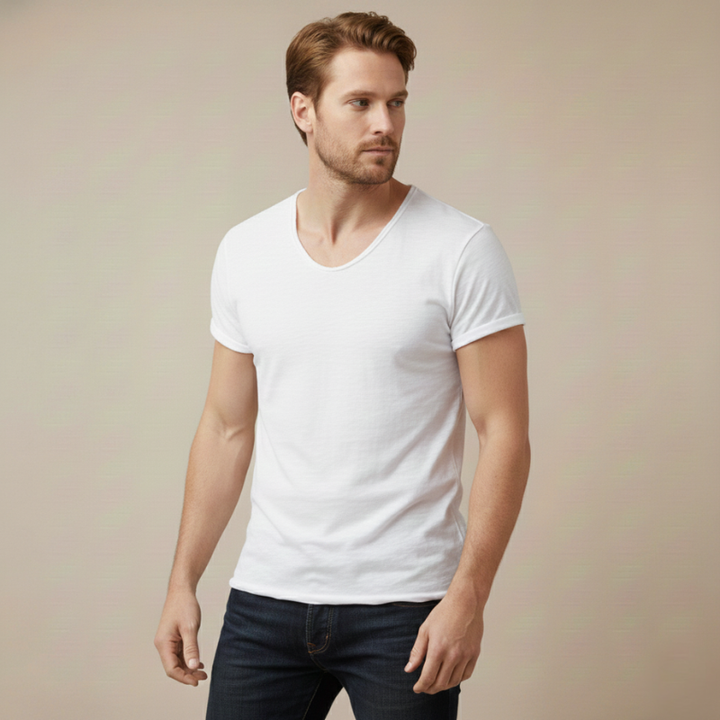 Male model wearing an white V-neck T-shirt styled with light pants in a simple studio background.