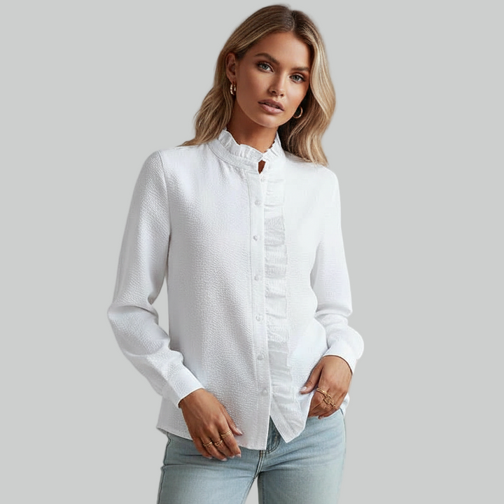 Woman wearing a white button-up shirt in a bright indoor room, showing a clean minimal fashion look.