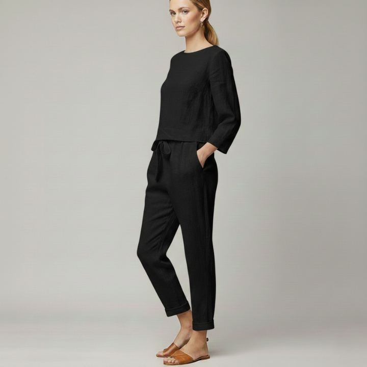 Woman walking in a black knit lounge outfit with a relaxed fit top and tapered jogger pants.