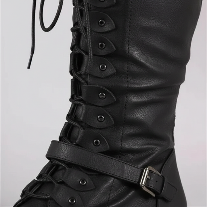 Black leather boot with detailed design on a light gray background