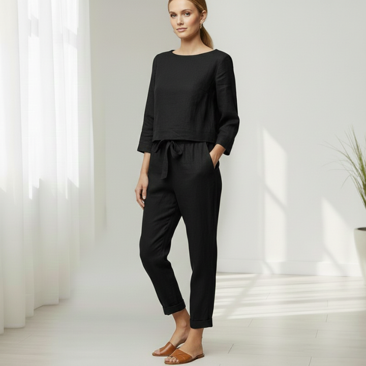 Woman standing in a black lounge set with a long-sleeve top and joggers styled for casual comfort.