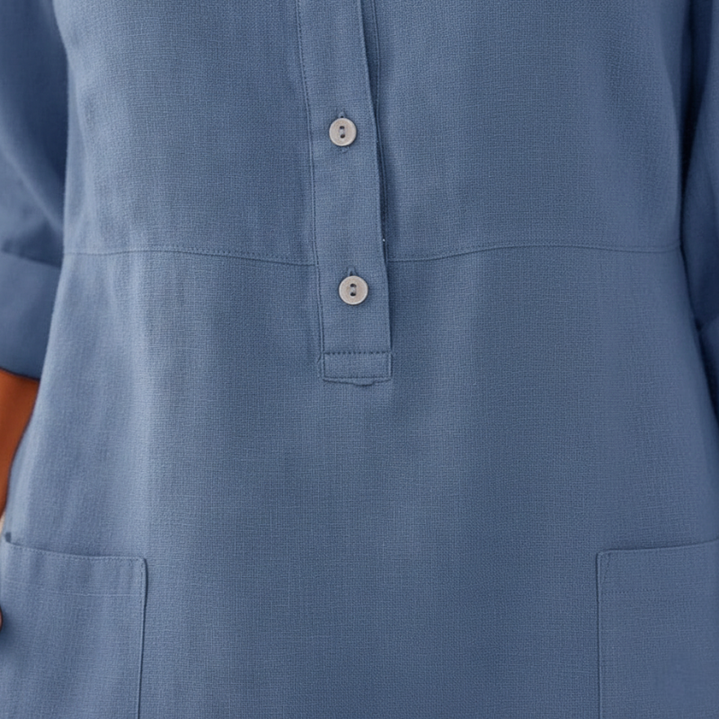 Female model in a blue linen-blend dress featuring 3/4 sleeves, a straight silhouette, and button neckline in studio lighting.
