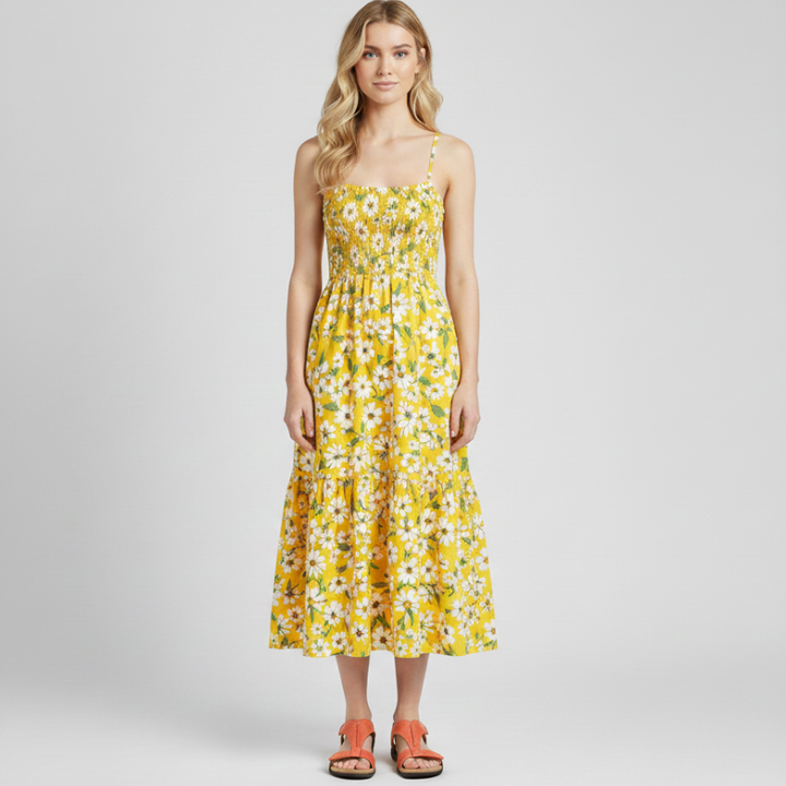 Woman standing in a yellow floral dress paired with black open-toe sandals in studio lighting.