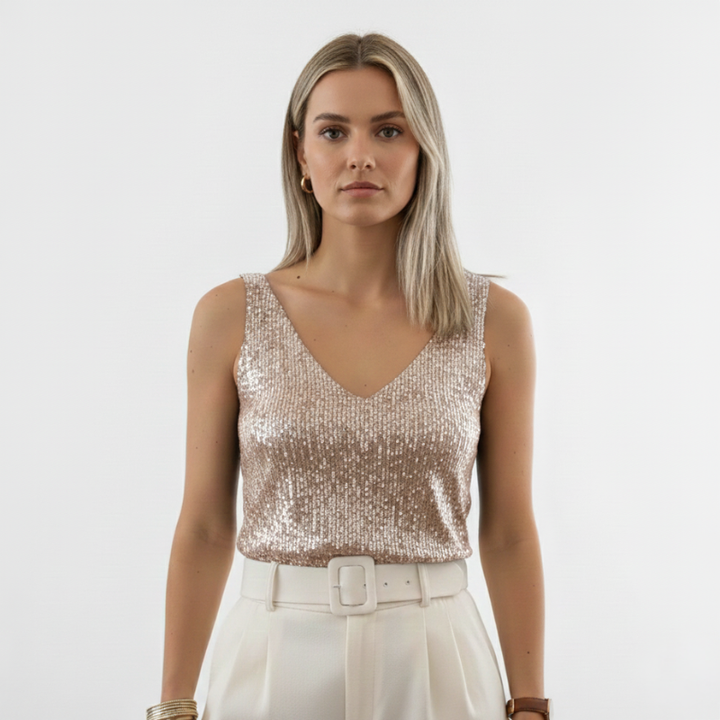 Woman wearing a champagne-colored sequin V-neck sleeveless top styled with white pants in bright studio lighting.