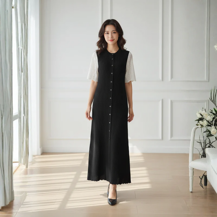 Woman wearing a black dress with white buttons in a bright room.
