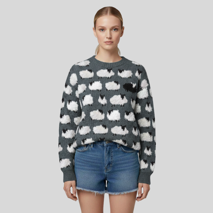 Woman wearing a gray knitted sweater with white cloud patterns, styled with denim shorts in studio lighting.