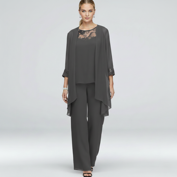 Woman wearing a gray two-piece chiffon pant suit with lace neckline and flowy layered top.