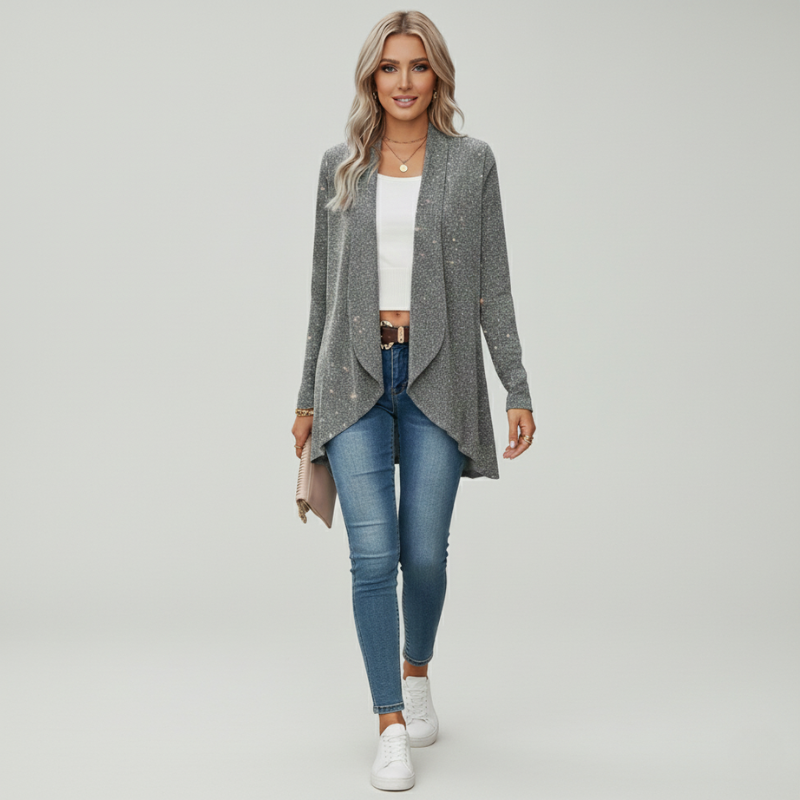 Woman wearing a gray cardigan, white top, blue jeans, and white sneakers on a light gray background