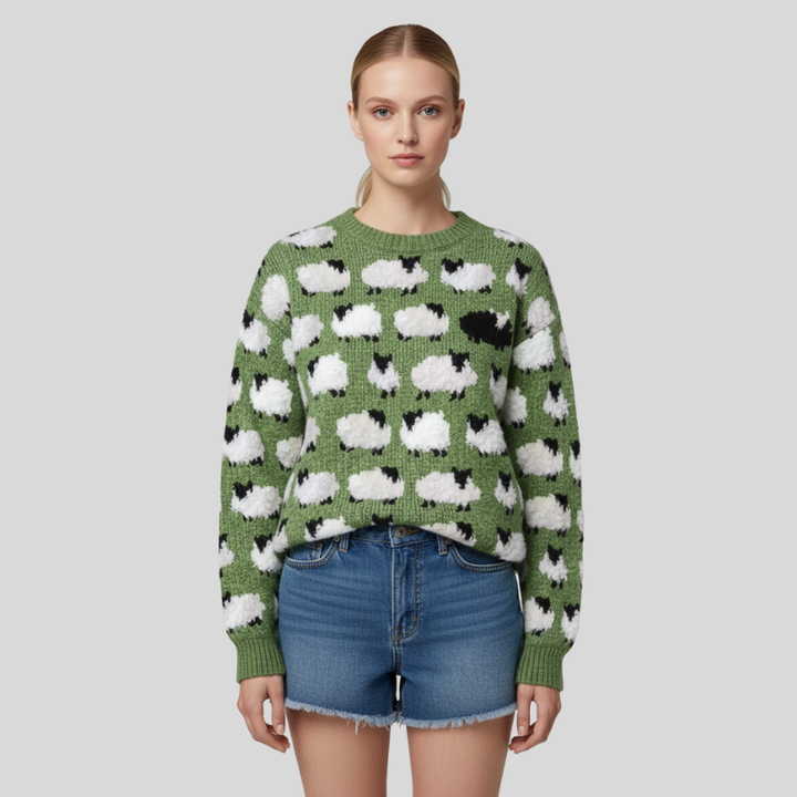 Woman wearing a green knitted sweater with white cloud designs in a simple indoor studio setting.