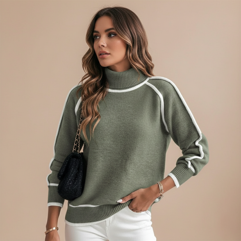 Woman wearing a green mock neck sweater with white contrast trim, styled with white pants in studio lighting.