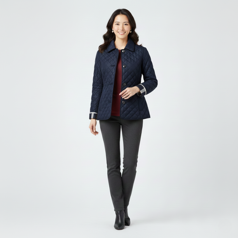Woman wearing a navy quilted jacket with black pants in a clean studio setting.