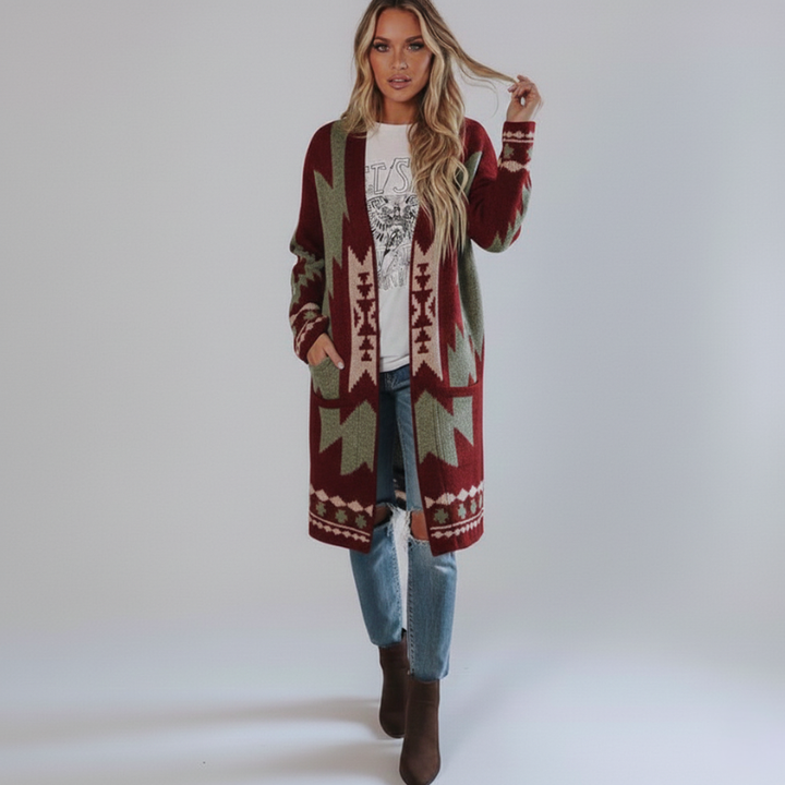 Female model wearing a long red and cream tribal knit cardigan styled with jeans in a bright studio setting.