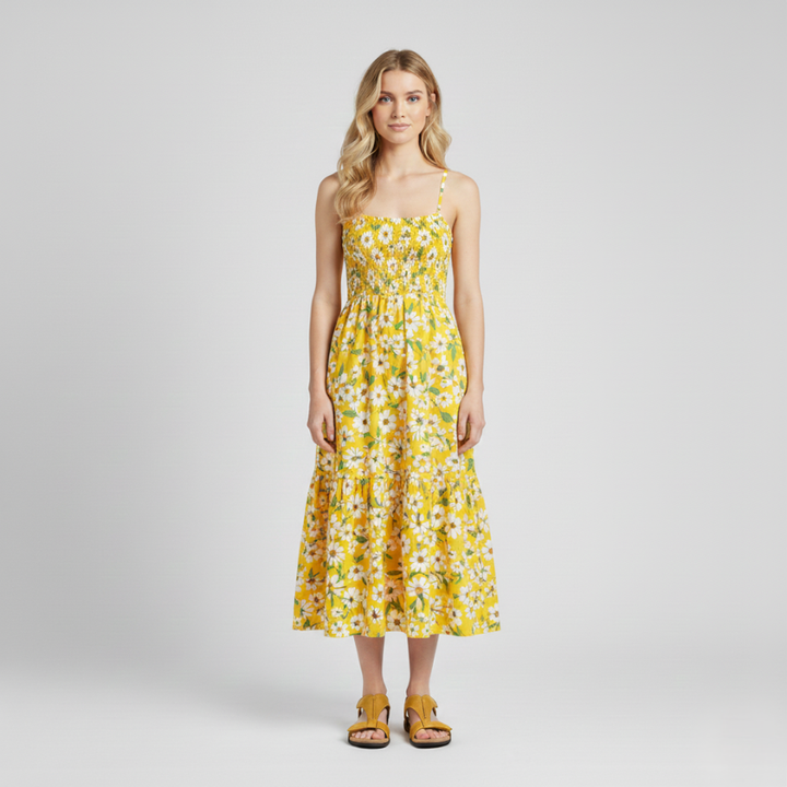 Woman wearing black sandals styled with a yellow floral dress in a bright indoor studio.