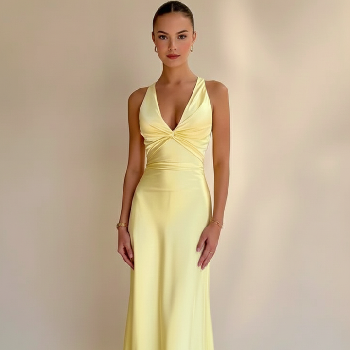 Woman standing in a yellow formal maxi dress with a fitted bodice and floor-length silhouette in a minimal studio setting.